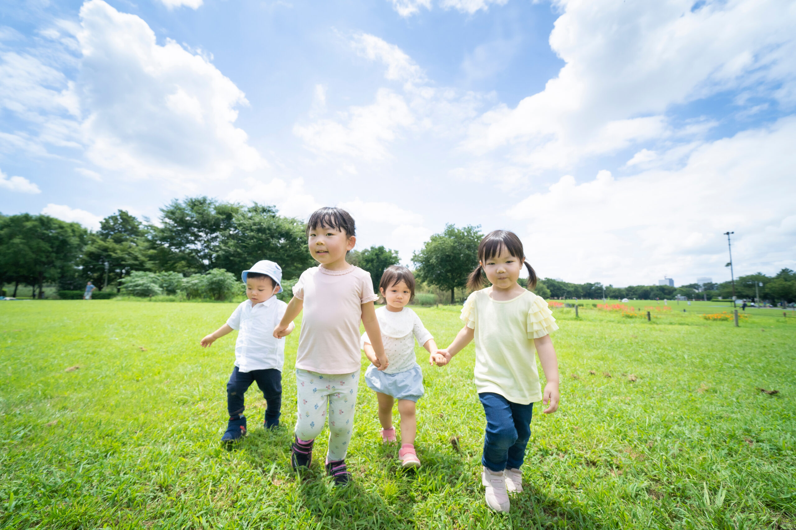 青空の下、手を繋いで元気に歩く子供たち