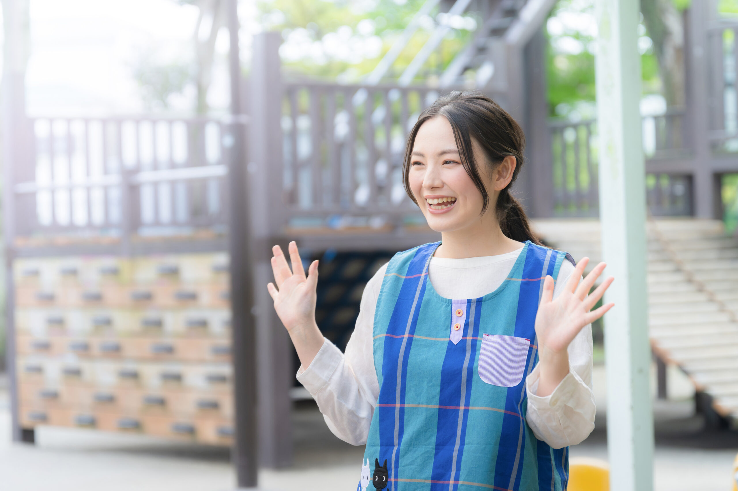 園庭で手を振る保育士 先生おはようございますorさようなら